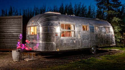 The Layby Lincs - themed vehicle glamping - Peggy Sue, a 1955 Airstream Cruiser, blends vintage 50s American diner charm with modern comforts, featuring a king-size bed, comfy sofa, and a retro pale blue and chrome decor.