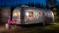 The Layby Lincs - themed vehicle glamping near Skegness - Peggy Sue, a 1955 Airstream Cruiser, blends vintage 50s American diner charm with modern comforts, featuring a king-size bed, comfy sofa, and a retro pale blue and chrome decor.